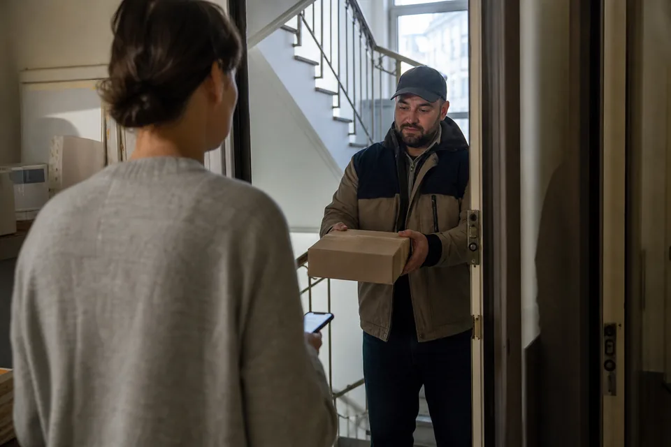 Courier handing a parcel to a customer at the door of a flat