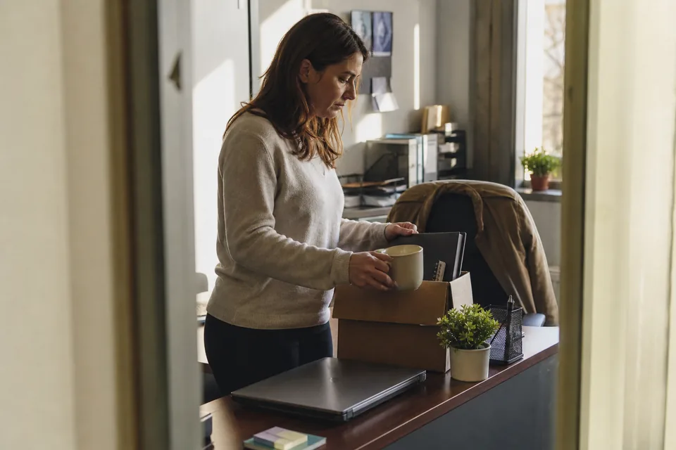 Employee packing a small box at her desk on her last day