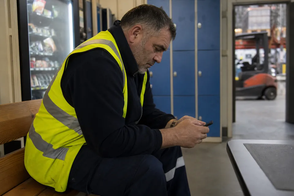Warehouse worker on a break answering a short staff survey on his phone