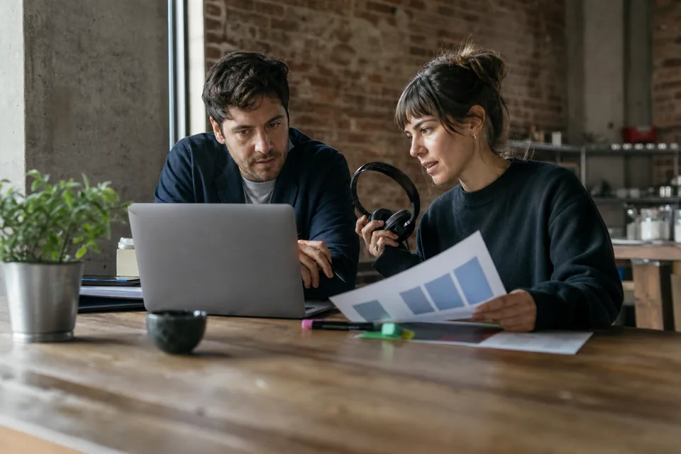 Two colleagues reviewing survey answers together at a loft office table
