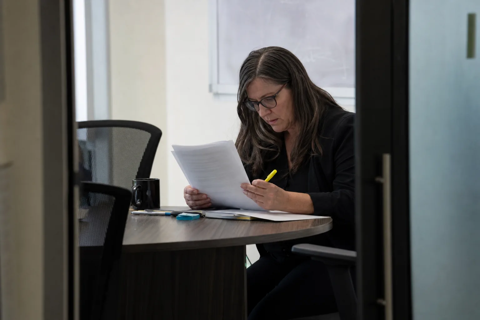 HR lead in a small meeting room reading printed quotes with a highlighter