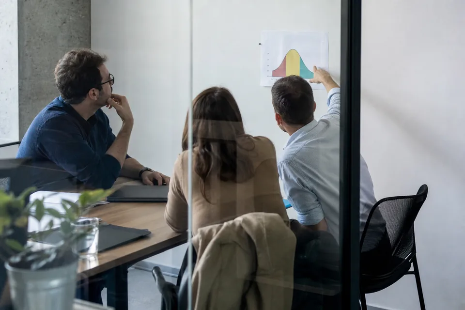 Team in a small meeting room reviewing a printed score chart split into three groups