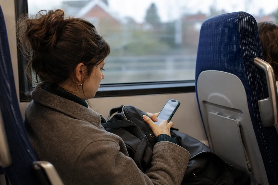 Commuter on a train typing a short text answer on her phone
